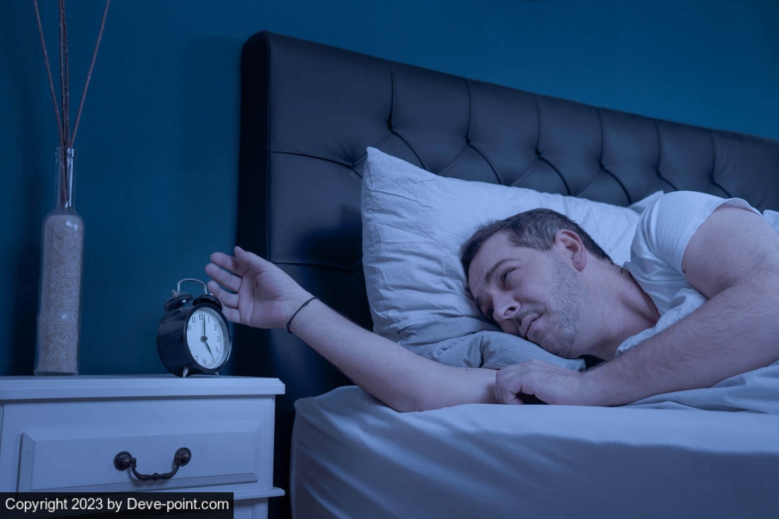 Man who cannot sleep looking at alarm clock G 1226563309